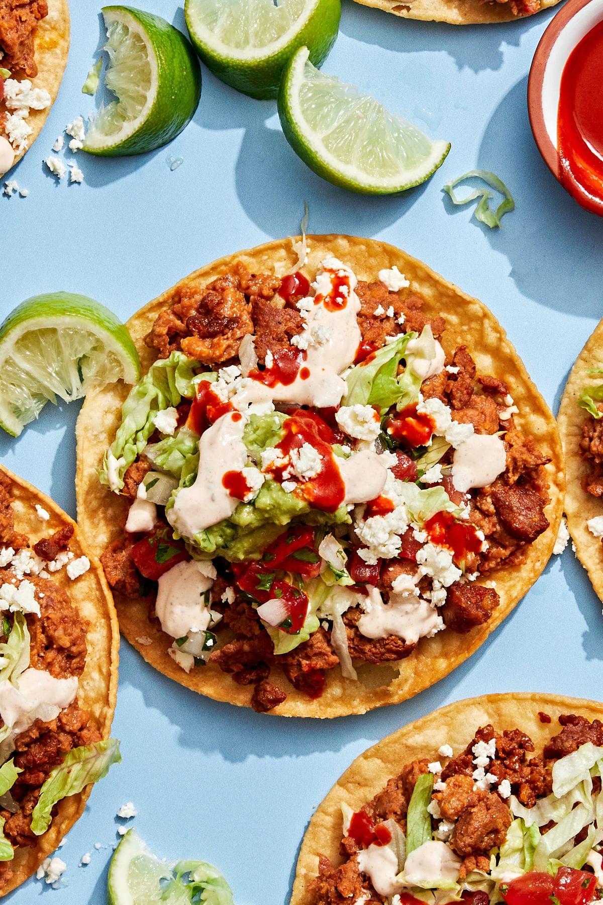 Easy tostadas with chorizo, refried beans, lettuce, cotija, pico de gallo, guac, and lime crema on crispy shells