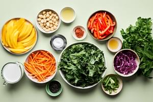 Kale, mango, cabbage, mint, cilantro, bell pepper, carrots & macadamia nuts in prep bowls to make a tropical kale salad