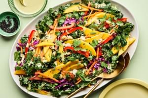tropical kale salad made with  mango, red cabbage, mint, cilantro, bell pepper, carrots, macadamia nuts and creamy dressing