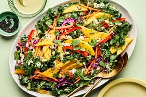 tropical kale salad made with  mango, red cabbage, mint, cilantro, bell pepper, carrots, macadamia nuts and creamy dressing
