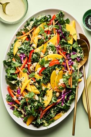 tropical kale salad made with  mango, red cabbage, mint, cilantro, bell pepper, carrots, macadamia nuts and creamy dressing
