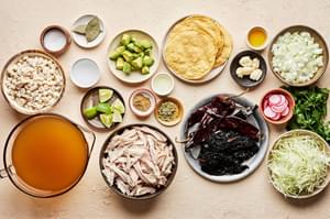 turkey, turkey stock, chiles, onion, garlic, spices and hominy in prep bowls to make turkey pozole rojo