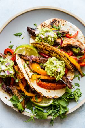 vegan Portobello Mushroom Fajitas on a sheet pan in tortillas on a plate