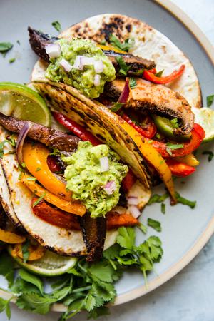 vegan Portobello Mushroom Fajitas on a sheet pan in tortillas on a plate