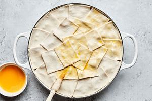 vegetable pot pie topped with raw puff pastry being brushed with egg wash