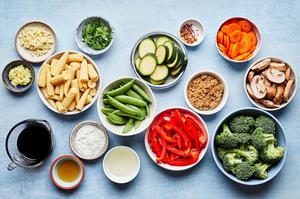 mushrooms, broccoli, corn, pepper, snap peas, zucchini & carrots in prep bowls for vegetable stir fry