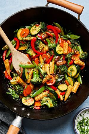 vegetable stir fry in a wok made with mushrooms, broccoli, corn, pepper, snap peas, zucchini & carrots with homemade sauce