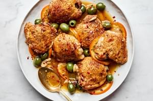 Vinegar chicken with oranges and olives, served with a rich sauce and garnished with red pepper flakes.