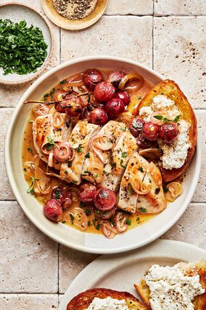 vineyard chicken sliced in a serving bowl with cooked shallots, parsley and red grapes