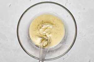 creamy dressing for waldorf salad being whisked in a glass bowl