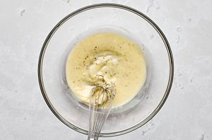 creamy dressing for waldorf salad being whisked in a glass bowl