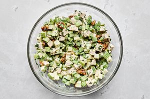 homemade waldorf salad with creamy mayo based dressing being tossed in a glass bowl