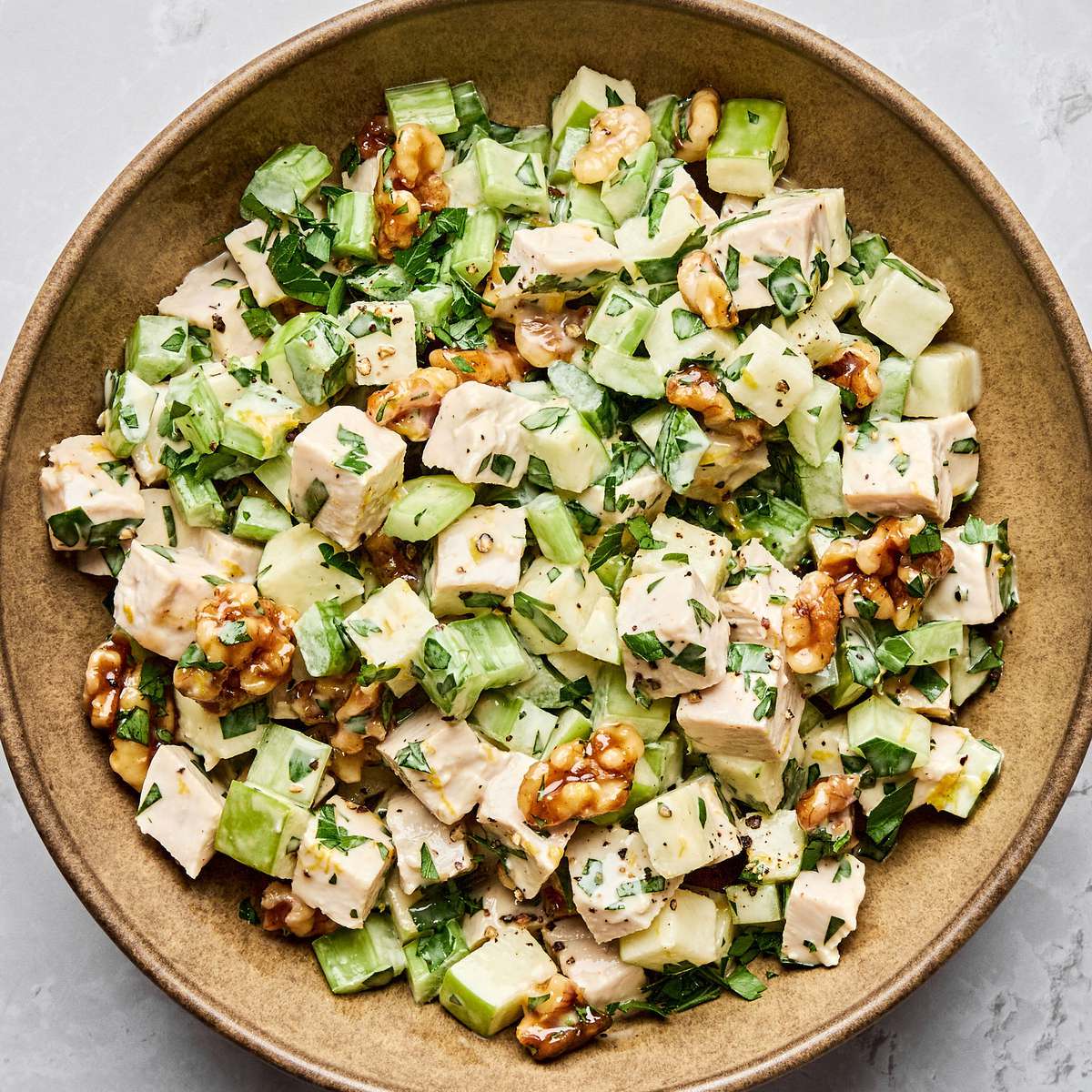 A fresh Waldorf salad made with crisp apples, celery, grapes, candied walnuts, and chicken tossed in a creamy dressing