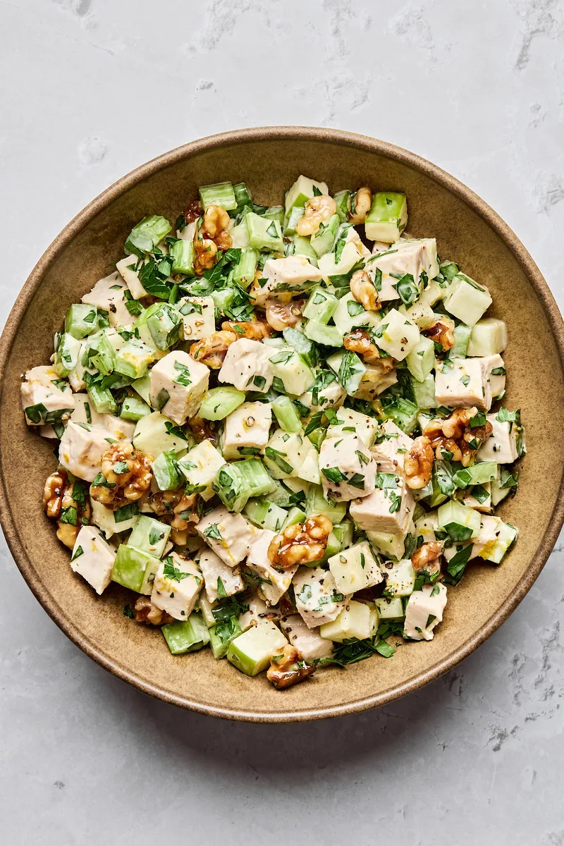 A fresh Waldorf salad made with crisp apples, celery, grapes, candied walnuts, and chicken tossed in a creamy dressing