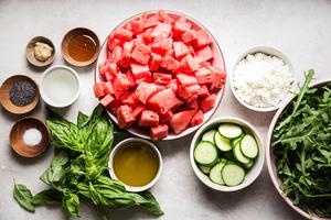 watermelon in a bowl, cucumber, arugula, feta, basil, olive oil salt pepper and poppyseeds