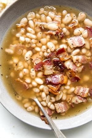 white bean and bacon soup in a bowl with a spoon