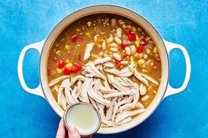 a pot of white bean chicken chili made with onion, green enchilada sauce, chiles, spices, corn and bell pepper