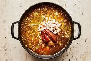 cannellini beans added to a pot with water, chicken broth, onion, celery, carrots spices, and ham hock