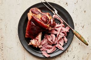 a cooked ham hock being cut into bite sized pieces