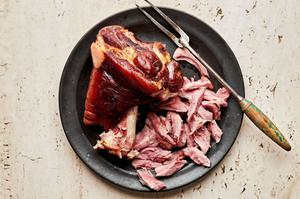 a cooked ham hock being cut into bite sized pieces