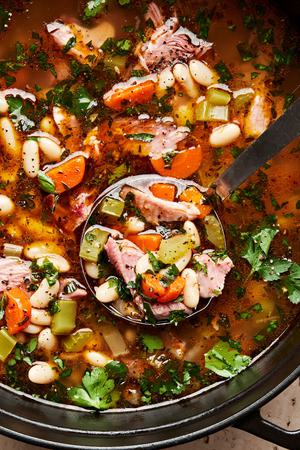 a pot of homemade white bean and ham soup with a ladle scooping some out
