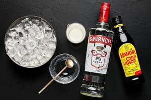 a bottle of vodka, a bottle of coffee liqueur, heavy cream, and ice to make a white Russian cocktail