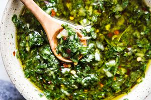 chimichurri sauce made with shallot, herbs , salt, pepper, olive oil, red wine vinegar next to a bowl of red pepper flakes