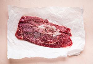 flank steak on parchment paper with salt and pepper