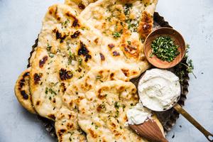 Herbed homemade flat bread with whipped feta cheese spread on a serving plate