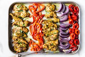 Sheet pan chicken shawarma with red bell peppers and red onion on a baking sheet