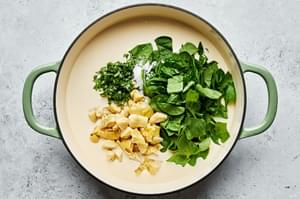 spinach, basil & artichoke hearts added to a pan with olive oil, garlic, butter, chicken stock, milk & cream cheese being