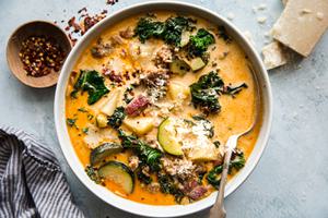 homemade zuppa toscana soup with sausage, potatoes and kale, parmesan cheese, and bacon in a bowl with a spoon