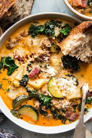 homemade zuppa toscana soup with sausage, potatoes and kale, parmesan cheese, and bacon in a bowl with a spoon
