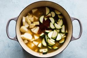 chicken stock, chili powder, onion, garlic, zucchini and potatoes cooked in a soup pot.