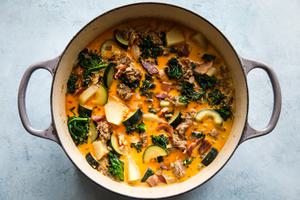 olive garden copycat zuppa toscana soup with sausage, potatoes and kale, parmesan cheese, and bacon in a soup pot